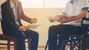 An injured man in a wheelchair is talking to a Social Security Disability appeals lawyer.