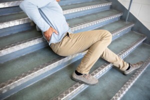 a man in a blue shirt lying on a staircase after injuring his spine