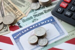 A Social Security card lying on a table with money and a calculator. Learn about the Social Security Disability benefits pay chart.